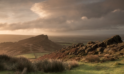 A dramatic rocky ridge landscape with dusky pink and grey clouds overhead