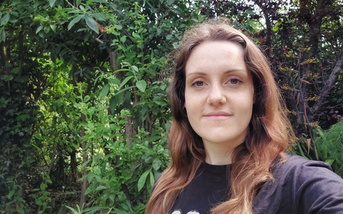 Katy smiling at the camera, with trees in the background