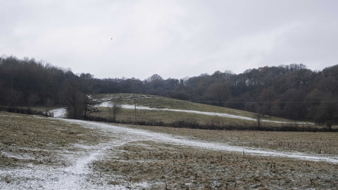 A countryside scene with rolling hills and some snow on the ground