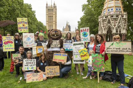 A group of people hold up colourful bold banners as they stand in front of Big Ben in London