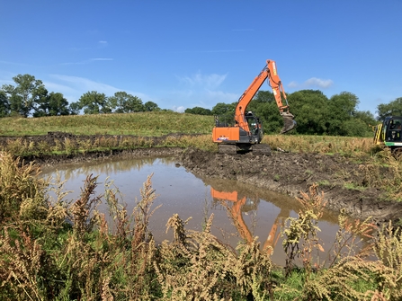 A bright orange machine scrapes the earth to make space for water