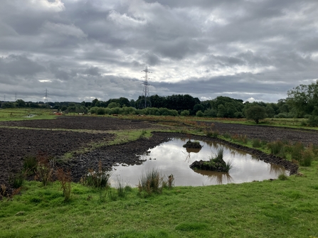 A newly made pond under a cloudy sky