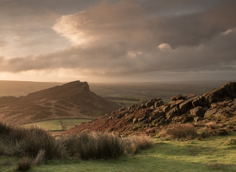 A dramatic rocky ridge landscape with dusky pink and grey clouds overhead